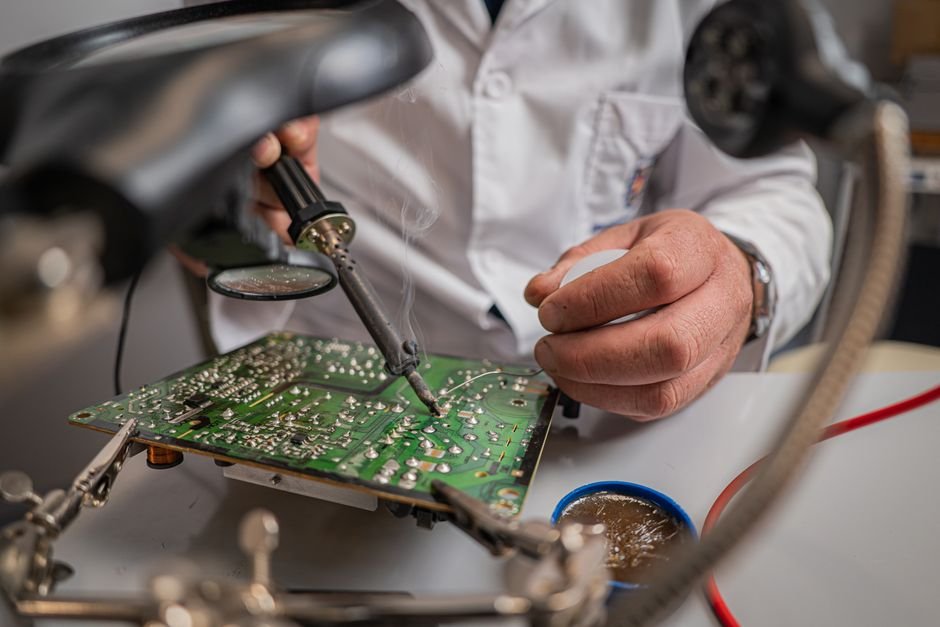 Engineer examining a circuit board at an electronics workbench