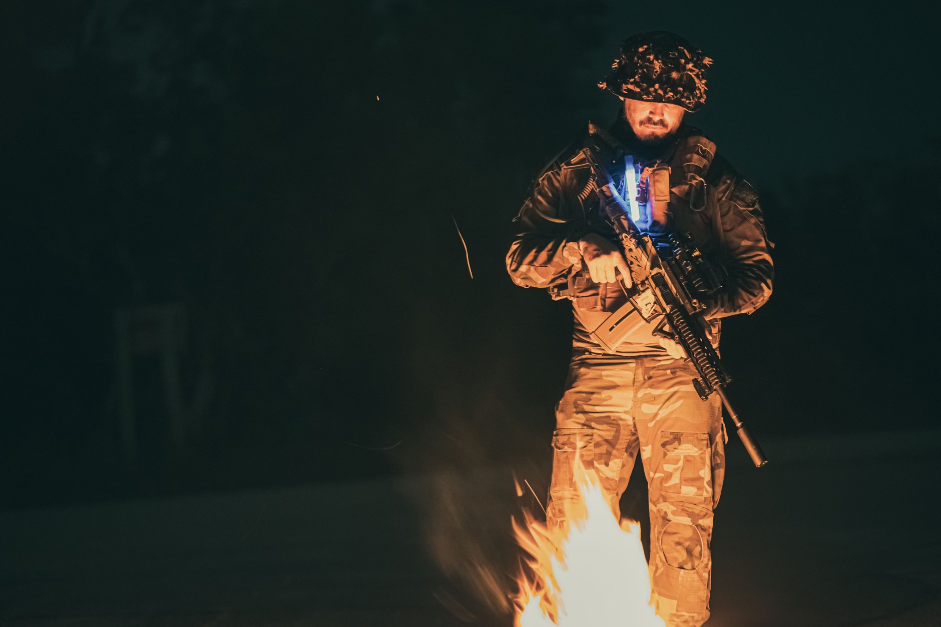 Night patrol moving through dark terrain wearing helmet-mounted night vision equipment